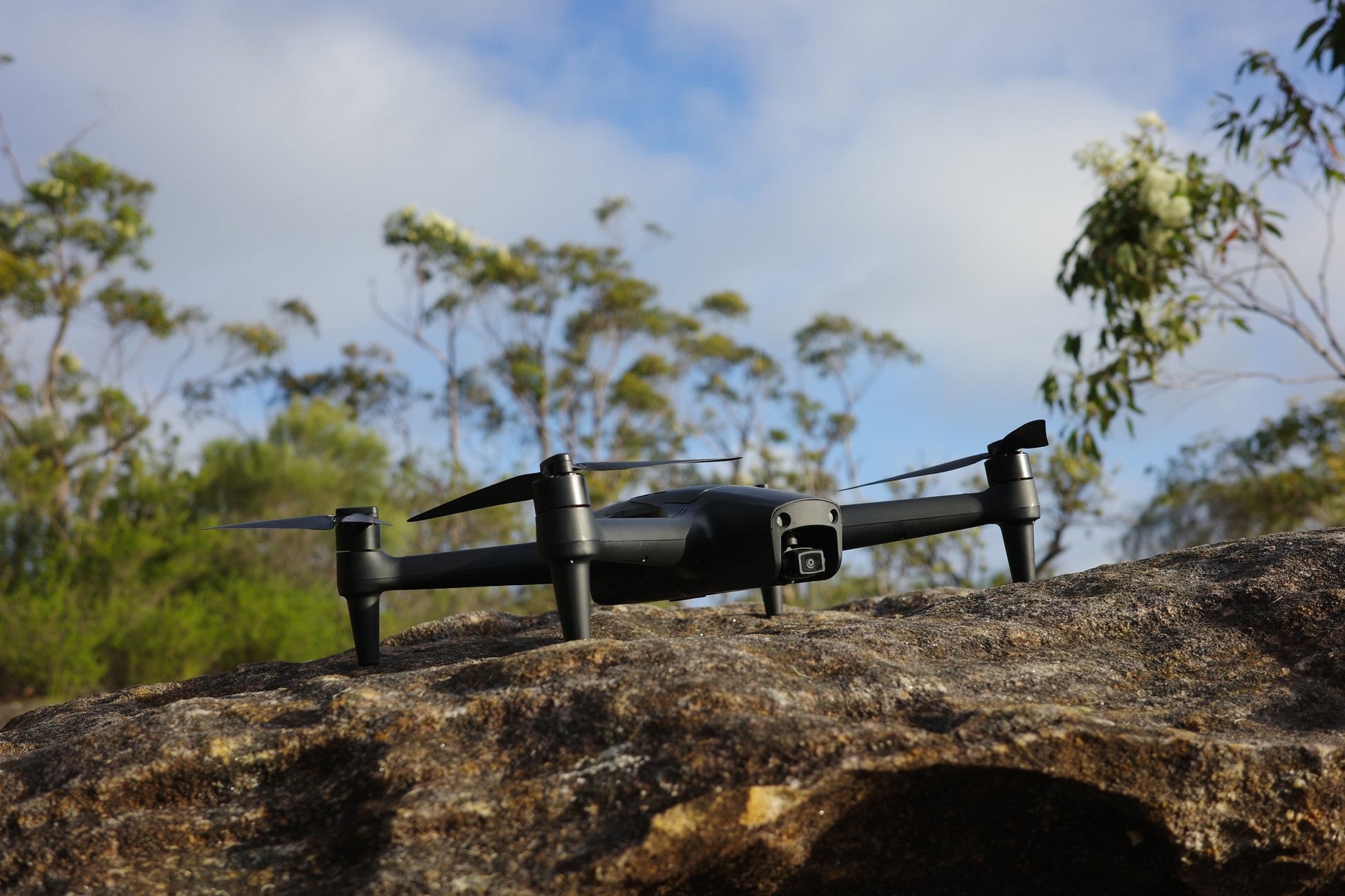 Aeroo Pro drone stationary on a rock with blue sky and trees in the background